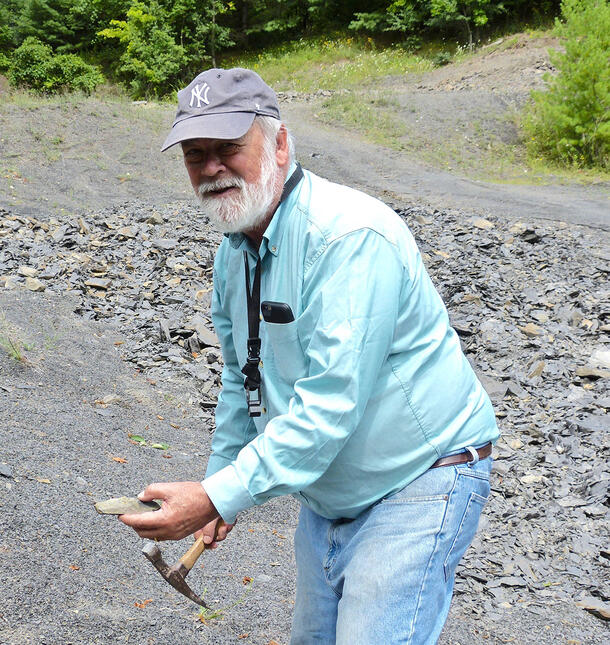 Niles Eldredge holds a chisel and a specimen at Devonian Quarry.
