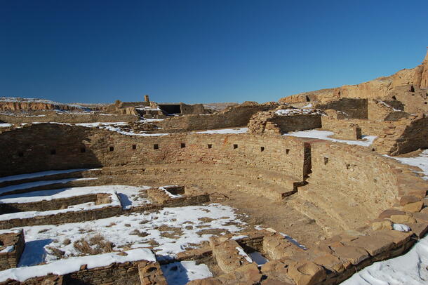 A photo of the sandstone ruins of Pueblo Bonito with a slight covering of snow