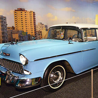 A vintage '50s car parked in the Museum, placed against a photo backdrop of Havana.