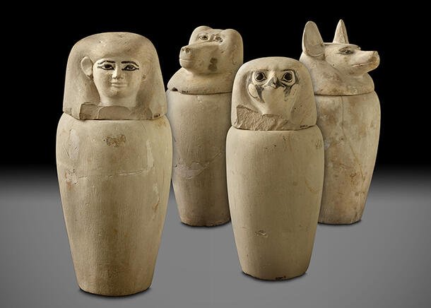 Four stone jars, the lids of which are shaped differently—one of which takes the form of a jackal, and the others represent a baboon, hawk, and human.