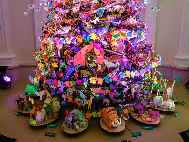 Bottom section of a Christmas tree decorated with origami animals, with various origami elephants ringing the bottom.