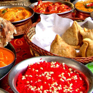 Close-up of many baskets of colorful prepared food on a table.