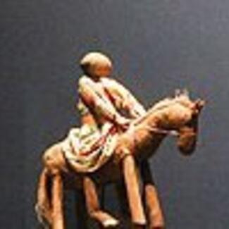 A figurine of a person astride a horse.