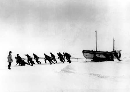 A team of men try to haul a boat across ice in a frozen flat environment.