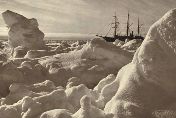 A ship visible in the background beyond large pieces of ice forming an almost rocky landscape.