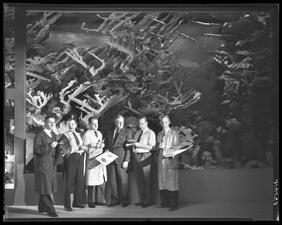 A group of six people stand in front of the nearly completed Andros Coral Reef display.