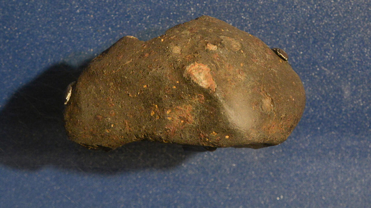 A meteorite that fell on L'aigle, France in 1803. A brownish rock with rusty reddish flecks on its surface.