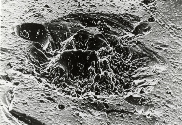 Black and white image of a microcrater on the Moon surface. 
