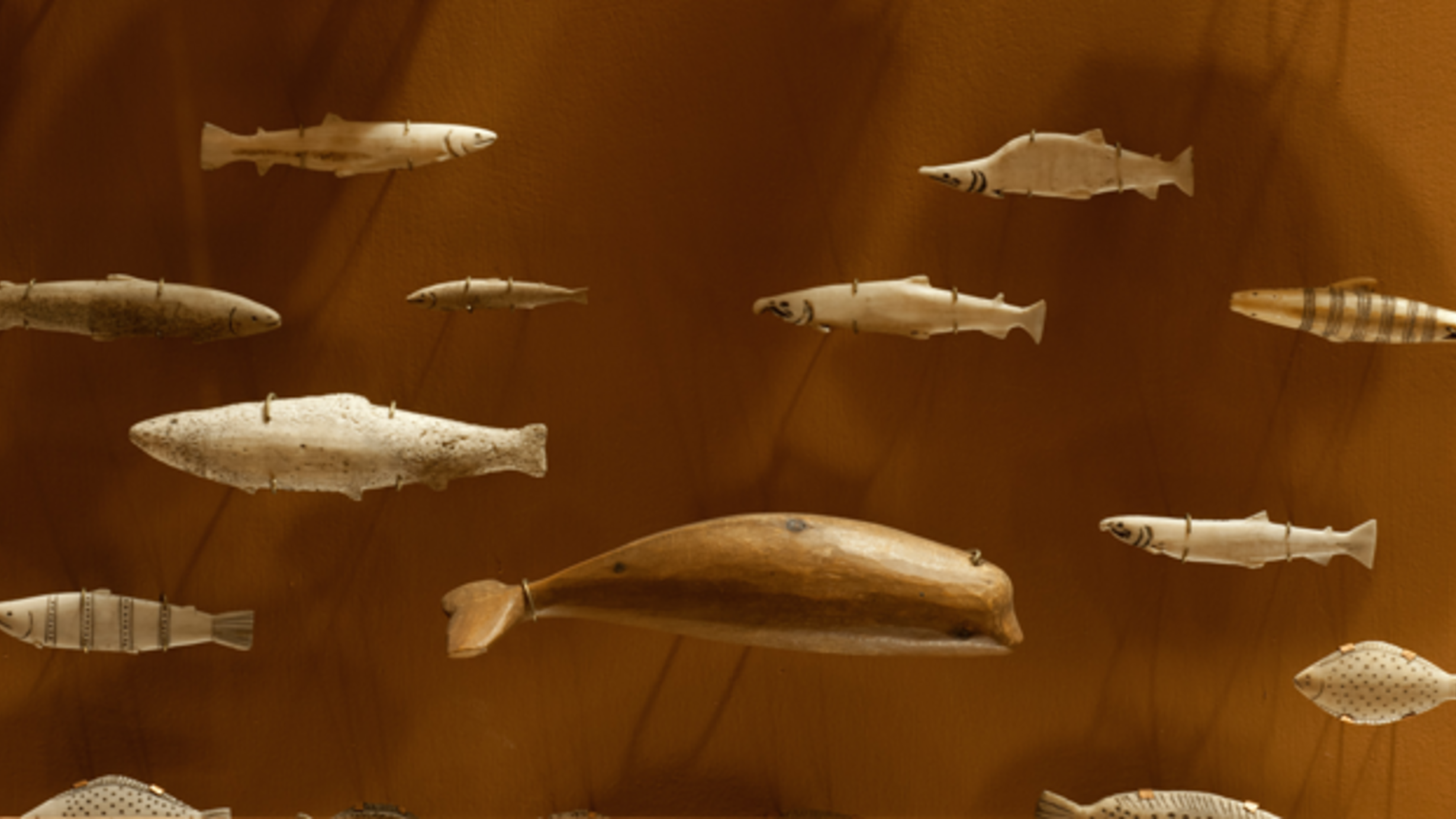 A small whale carved of wood with several other carved figurines of assorted fish.