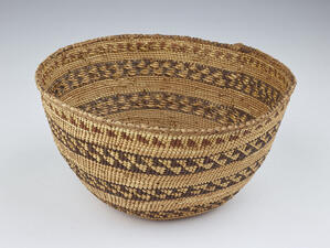 Round woven basket decorated with alternating lines of geometric patterns and plain weaving.