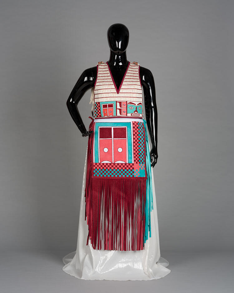 A mannequin wearing a striped vest and a patterned, fringed skirt.