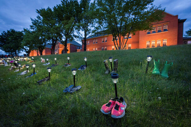 Pairs of children's shoes are lined up in two rows on the lawn in front of the former Kamloops Indian Residential School.