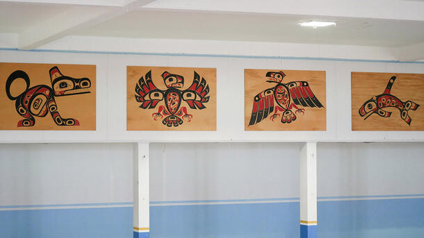 Four wooden rectangles, each featuring a stylized painted animal figure, hanging in a row on a white wall.