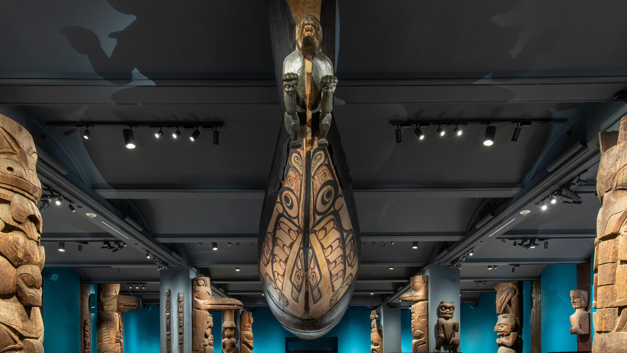 An immense canoe with a prow in the form of a wolf hangs from the ceiling of a Museum hall.