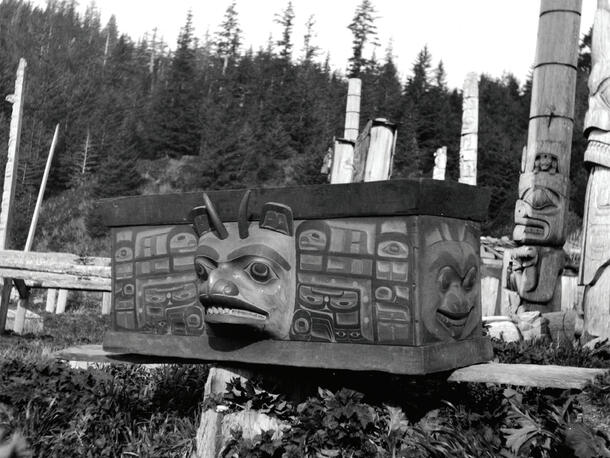 Historical image of Chief Gidansda’s Moon and Mountain Goat Chest on a plank near totems.