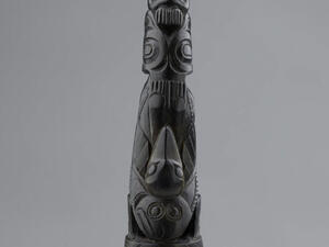 Carved piece with a beaked figure and other carved patterns. 