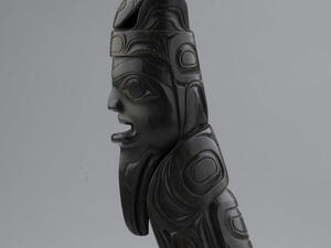 Carved sculpture of stylized woman with a labret mouth piercing.