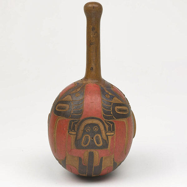 Round wooden rattle carved and painted with the face and claws of a land otter.
