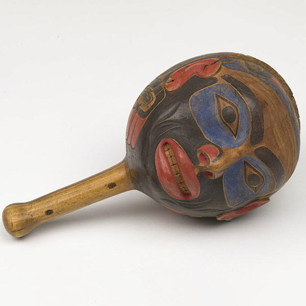 Round wooden rattle carved and painted in the shape of a human face.