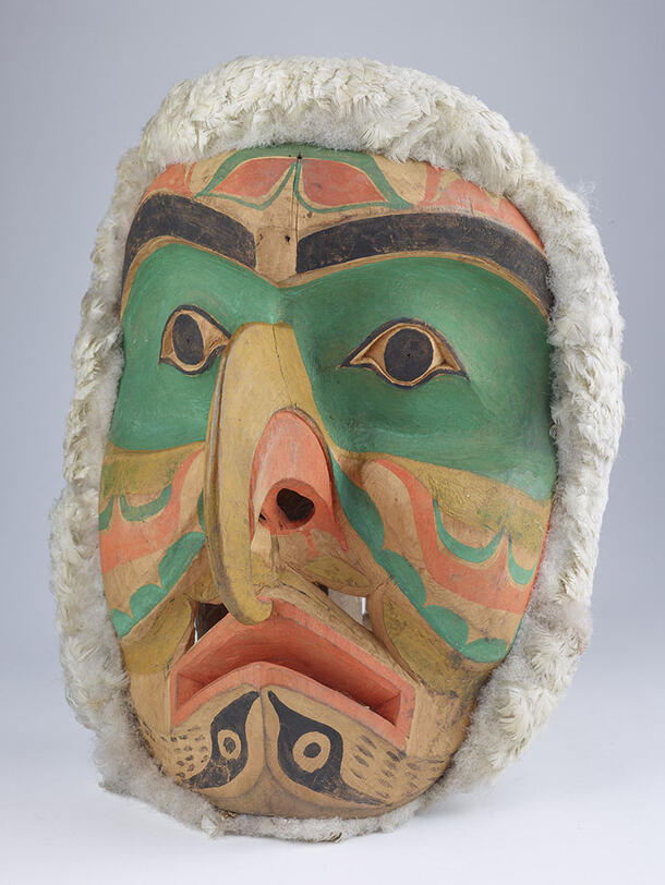 Carved wooden mask in the shape of a human face with an eagle's beak.