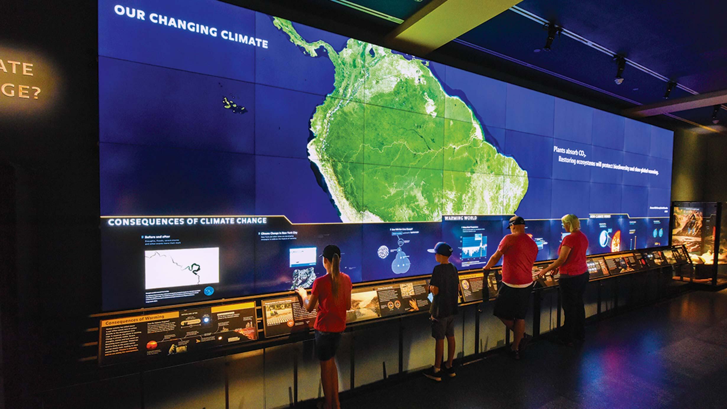 Visitors interact with the digital climate change wall in the Hall of Planet Earth.