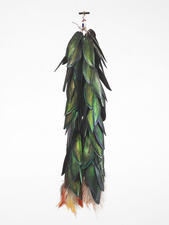 Dangling ornament made of iridescent, layered green feathers and white and orange feathers at the bottom.