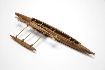 Model of a long wooden canoe with a second hull.