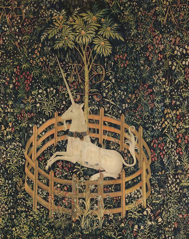 Close-up of tapestry image of a unicorn sitting in a circular gated enclosure among trees, flowers and leaves.