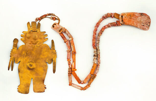Thin, flat human-shaped figure shaped from gold alloy, attached to a necklace formed of beads.
