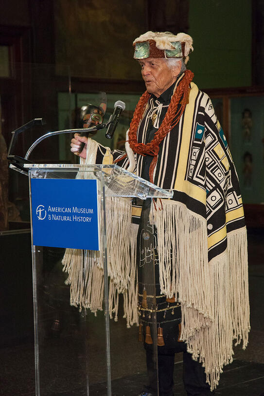 Man in ceremonial dress stands at a podium and speaks.