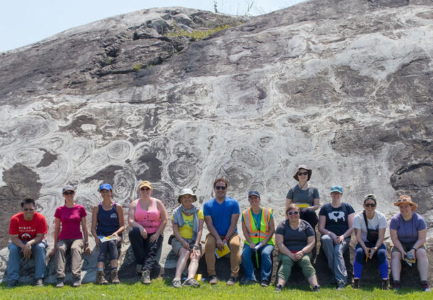 MAT alumni with Associate Curator Melanie Hopkins sitting in front the Allentown Dolomite formation.