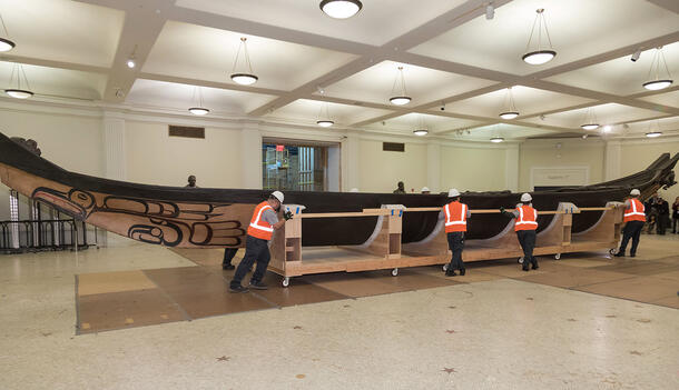 Workmen begin to move the Great Canoe out of the Grand Gallery.