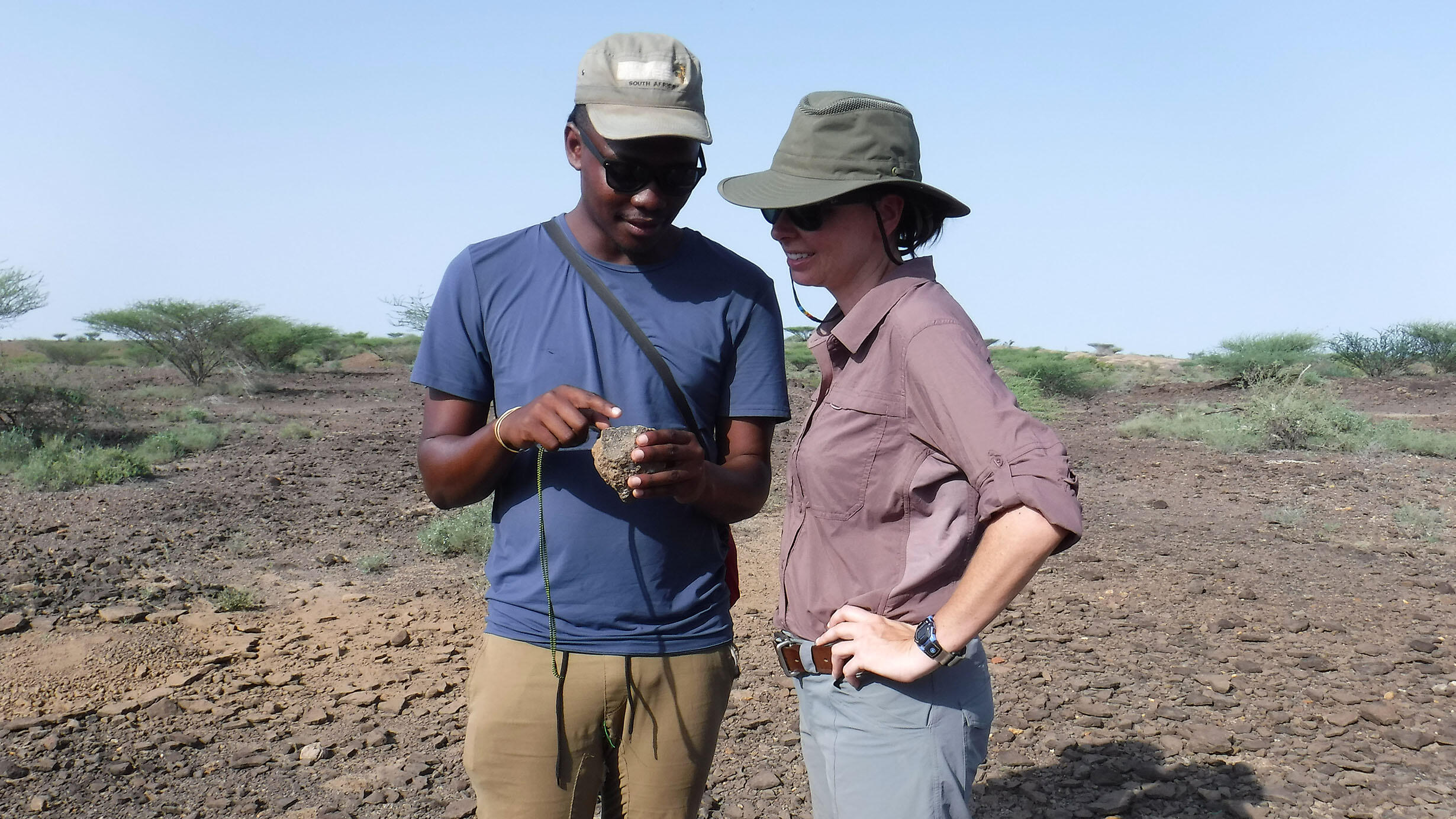Two scientists in the field examine a specimen together.