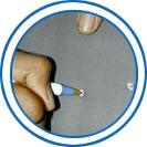 A hand piercing a flat dark surface with the tip of a ballpoint pen.