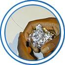 Two hands compressing metal foil into a small-to-medium size ball.