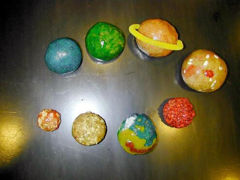 Closeup of 8 cookie balls decorated to look like the planets of our solar system.  