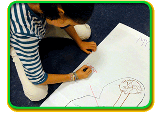A child sits on the floor and draws a diagram of the chest area of the nervous system with markers on a large piece of paper.