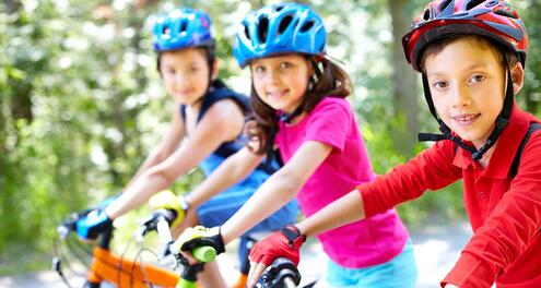 Three kids on their bikes wearing helmets