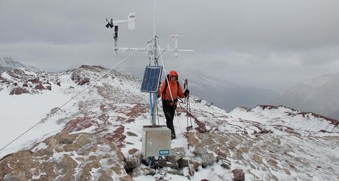 Scientist collecting data from weather station located at snowy mountain