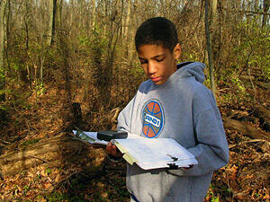 boy in the woods recording data