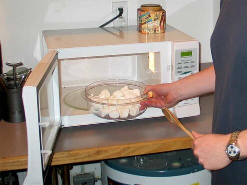 an adult places the bowl with contents into the microwave