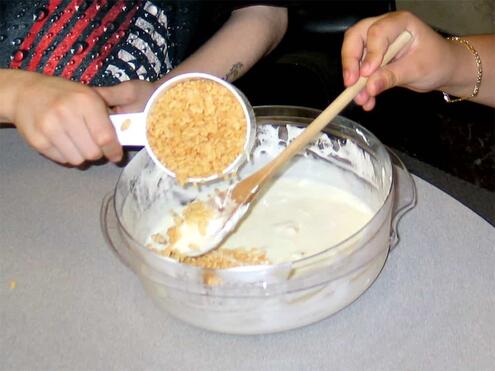 pouring the Rice Krispies into marshmallow butter mixture