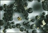 More than fifty dark spheres, called chondrules, against light-colored background.