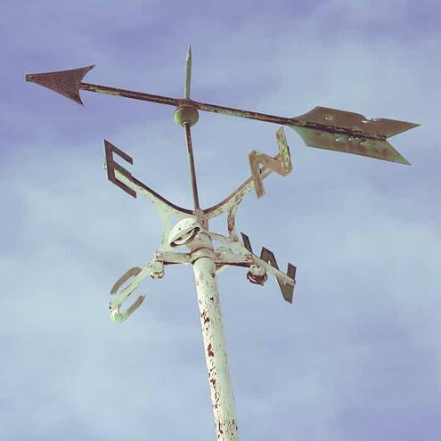 white metal wind vane with arrow and north, south, east, west, directions
