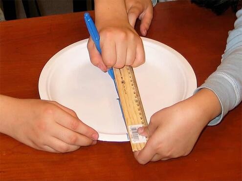 using a ruler guide to draw a line across middle of paper plate