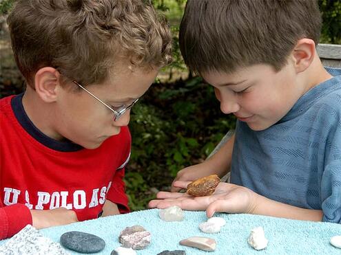 2 boys looking closely at one of the rocks they collected