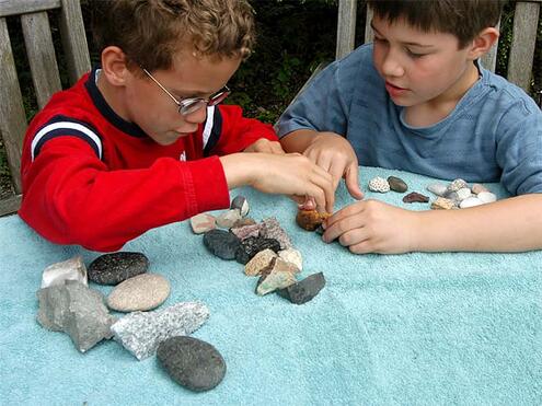 2 boys arranging their collected rocks into groups