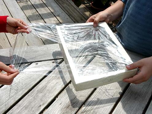 showing a box top with square cut out and covering with plastic wrap to make a window
