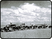 A historical photograph of a caravan of eight cars in the Gobi Desert.