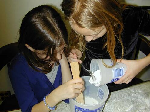 girls pouring in plaster of Paris and mixing